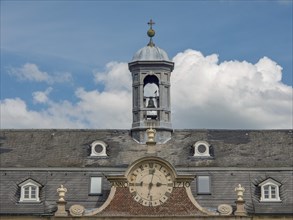 A clock tower on a historic castle under a blue sky with white clouds, old red brick castle with