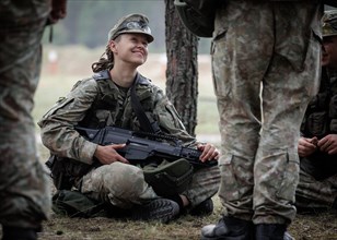 Young Lithuanian female reserve soldier sitting on the floor during her lunch break during her
