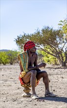 Traditional Hakaona man sitting on a stool, Angolan tribe of the Hakaona, near Opuwo, Kunene,