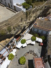 Aerial view of a Spanish village with narrow streets and stone wall, surrounded by buildings and