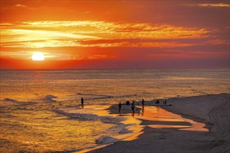 People playing and fishing on the beach at sunset on the Gulf of Mexico at Gulf Shores, Alabama,