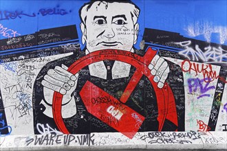 Mural shows a man with a steering wheel, police uniform, overlaid with numerous graffiti and