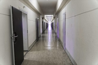 A long corridor with open grey doors and neon lighting in an old building, Berlin-Hohenschoenhausen