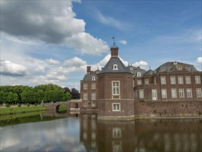 Historic red brick castle, situated on a moat with a small bridge, under a cloudy sky, old red