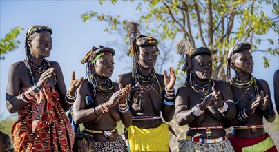 Hakaona woman with traditional kapapo hairstyle, clapping and laughing, Angolan tribe of the