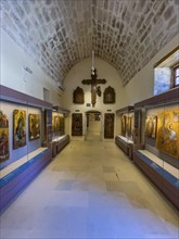 Entrance area with showcases and large wooden cross on wall in vaulted museum Monastery museum in