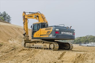 Hyundai backhoe parked at base of dirt hillside at construction site in Daejeon, South Korea, Asia