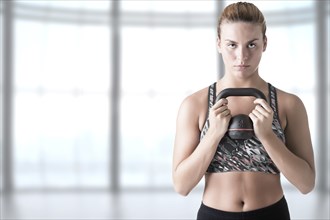 Fit woman working out with a kettlebel and similingl in a gym