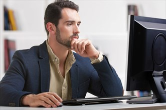 Man looking at a computer screen, thinking about the job at hand