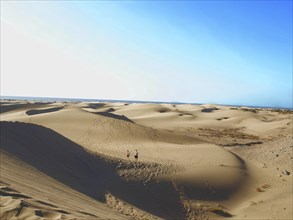 People walking in a desert, blue sky