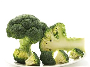 Broccoli standing, laying and in pieces towards white background