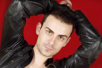 Portrait of a young man with black leather jacket over a red background