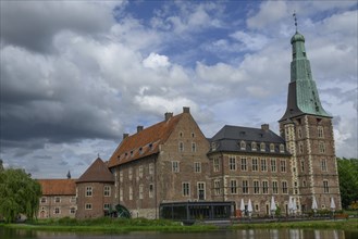 Large historic castle with towers and tiled roofs next to a lake, Raesfeld, North Rhine-Westphalia,