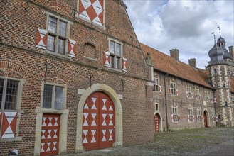 Historic building with richly decorated brick façades and red and white patterned doors and