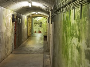 Damp and abandoned tunnel with moss-covered concrete walls and gloomy lighting, helgoland, germany