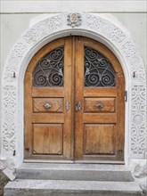 Antique wooden door with ornately carved archway and metal grilles in a historic building, lindau,