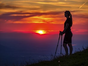 Silhouette of a young slender woman with hiking poles on a mountain meadow at sunset, Schlenken,
