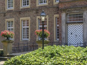 A brick building with a lantern in front of the entrance and flower boxes on the windows, ochtrup,