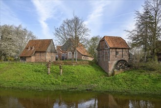 Small historic village with farmhouses, windmill and a river with a water wheel in a rural