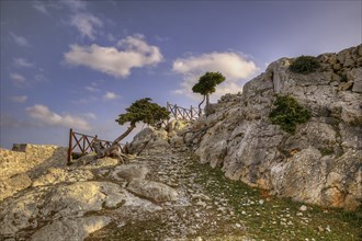 HDR, Rocky landscape with stony path, wooden fence and scattered trees under the blue sky, Kastro