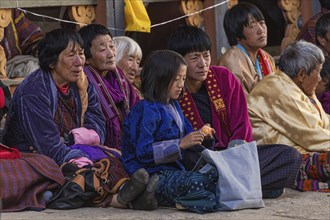 Bhutanese people in traditional clothes watching the annual Tsechu of Trongsa Dzong, Bhutan, Asia