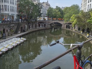 Urban scene with a canal, small boats, a bridge and a bicycle attached to the railing, utrecht,