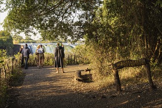 Tourists looking at the Victoria Falls on Zambezi River located at the border of Zambia and