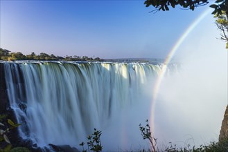 Scenic view of rainbow arching the Zambezi river waterfall of Victoria Falls in Zimbabwe