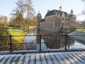 View of a castle from a bridge, surrounded by water and wintry parkland, ruurlo, gelderland,