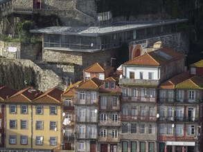 Historic buildings with red roofs on the hillside of a city bordered by a stone wall and modern