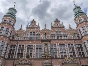A magnificently decorated historic building with statues and a cloudy sky, Gdansk, Poland, Europe
