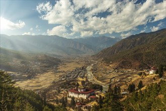 Sunrays through the clouds as the sun is setting over Paro