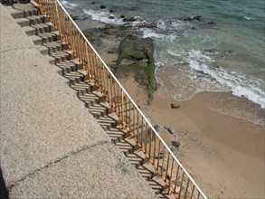 A steep, stone staircase leads down to a rocky stretch of coast, ajaccio, corsica, france