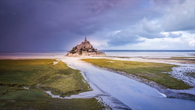 Le Mont Saint-Michel tidal island with deep blue water in golden evening light