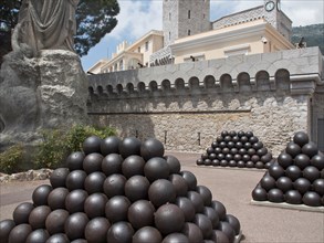 Courtyard of a castle with stacked stone balls and a large statue, monte carlo, monaco, france