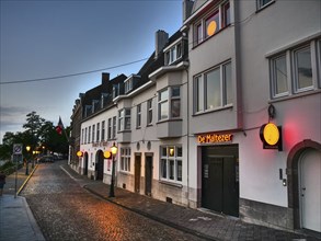 Narrow alley with illuminated windows at dusk, representing urban lighting, Maastricht, limburg,
