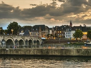 Old bridge over a river, surrounded by illuminated buildings and historic old town flair,