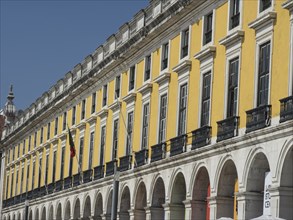 Long yellow façade with arcades in a sunny city scene, Lisbon, portugal