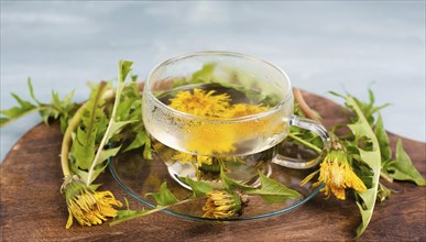 Dandelion wildflower tea, glass with herbal hot drink, alternative medicine for detox, leaves and