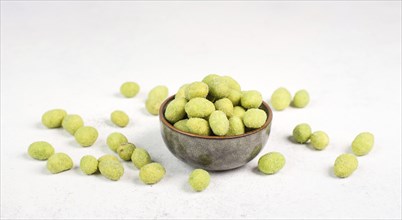 Pile of green wasabi coated peanuts in a bowl, spicy snack, oriental food