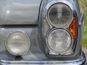Close-up of a grey vintage car, showing the headlights and chrome trim, winterswijk, gelderland,