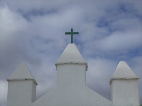 White church tower with green cross under a cloudy sky, arrrecife, lanzaorte, canary islands, spain