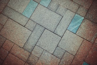 Geometric pattern of pavement tiles in blue and brown tones, creating a textured urban flooring