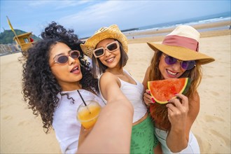 Multiethnic female friends enjoying summer on the beach on vacation, outdoors smiling and laughing