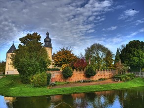 Castle with moat and autumn vegetation under a cloudy sky, gemen, münsterland, westphalia, germany