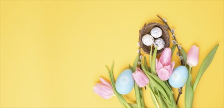 Nest with small eggs and pink tulips on a yellow colored background, easter holiday greeting card,