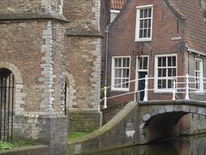 Traditional view of an old brick building with a small bridge over a canal, Delft, Holland,