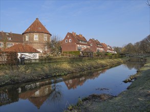 A calm river flowing past several houses and reflecting them in the water, Coesfeld, münsterland,