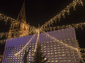 Christmas illumination with twinkling lights and tower in the background at night, Ahaus,