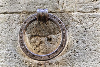 Volterra, Tuscany, Italy, Europe, Close-up of an antique metal door knocker on a stone wall, Europe